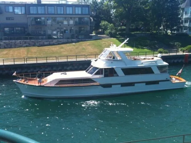 1974 Pacemaker Cockpit Motoryacht cruising on a sunny day near waterfront buildings.