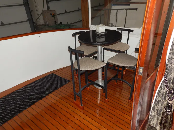 Top Coat Yacht Photos Pics 1974 Pacemaker Cockpit Motoryacht interior with wooden flooring and a round table with chairs.