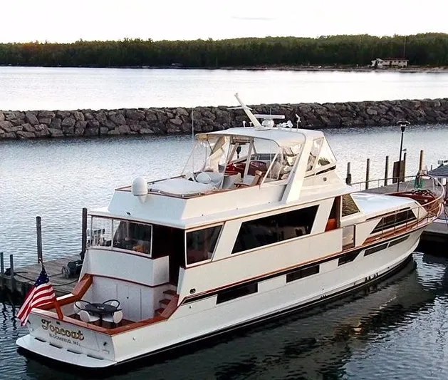 Top Coat Yacht Photos Pics 1974 Pacemaker Cockpit Motoryacht docked by a stone breakwater, displaying an American flag.