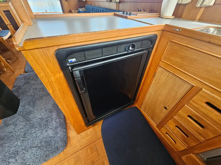 Marytime Yacht Photos Pics 1987 Grand Banks 42 Europa interior with compact black fridge and wooden cabinetry.