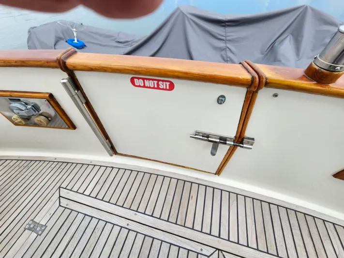 Marytime Yacht Photos Pics Grand Banks 42 Europa 1987 boat deck with "Do Not Sit" sign on wooden railing.