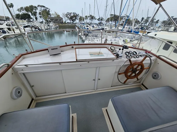 Marytime Yacht Photos Pics 1987 Grand Banks 42 Europa yacht helm with wooden wheel, marina view, and nautical instruments.