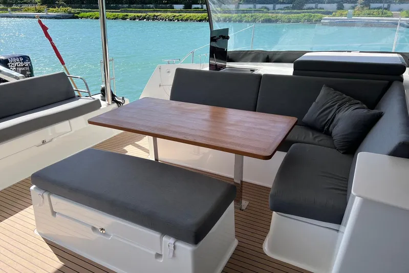 Portlish Yacht Photos Pics Outdoor seating area on 2022 Fountaine Pajot Tanna 47 catamaran with wooden table and cushions.