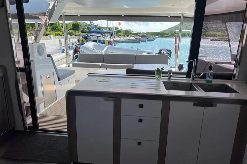 Portlish Yacht Photos Pics Interior view of 2022 Fountaine Pajot Tanna 47 yacht with kitchen and outdoor seating.