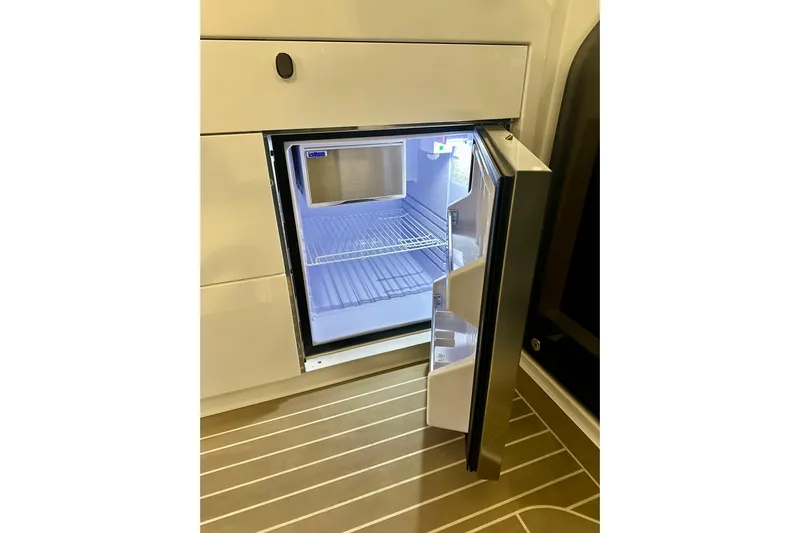 Delphin Yacht Photos Pics Open refrigerator inside 2023 Nimbus Weekender 9 boat, showcasing interior shelves.
