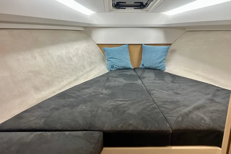 Delphin Yacht Photos Pics 2023 Nimbus Weekender 9 cabin interior with cozy bedding and blue pillows.