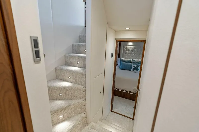 Mana Yacht Photos Pics Interior of 2021 Viking 82 Cockpit Motor Yacht with elegant staircase and cozy bedroom.