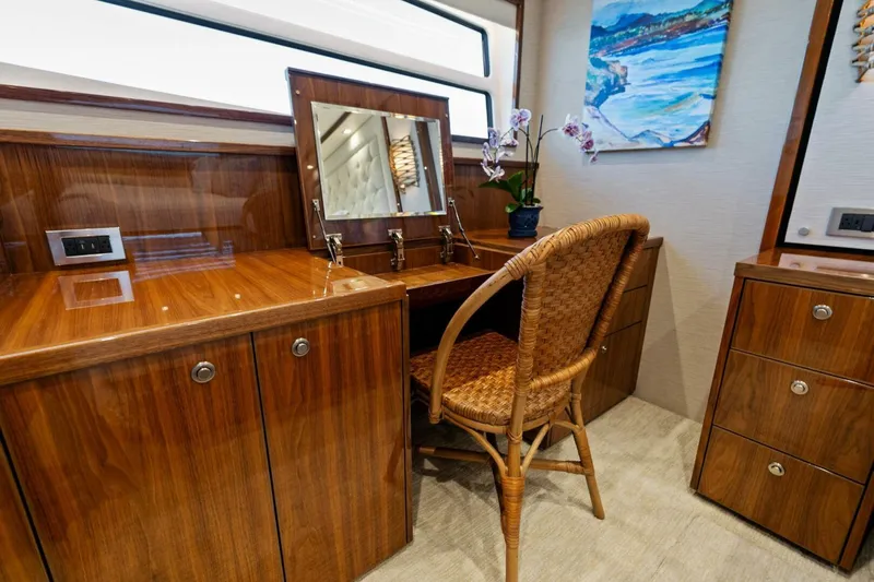 Mana Yacht Photos Pics Luxurious vanity area on 2021 Viking 82 Cockpit Motor Yacht with wood finish and wicker chair.