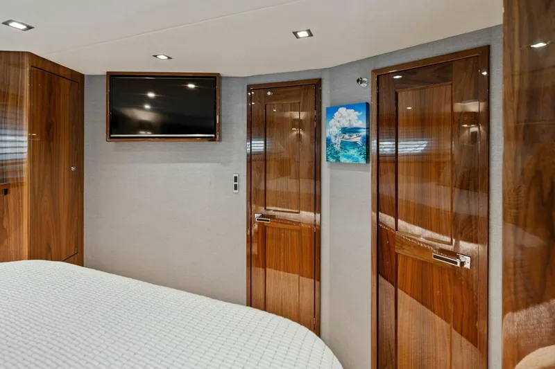 Mana Yacht Photos Pics Luxurious cabin interior of 2021 Viking 82 Cockpit Motor Yacht with wood finishes and TV.