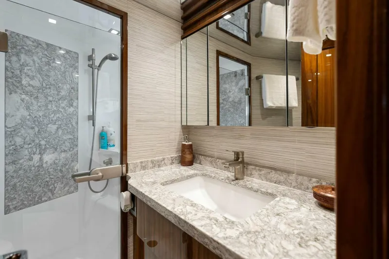 Mana Yacht Photos Pics Luxurious bathroom in 2021 Viking 82 Cockpit Motor Yacht with marble countertop and glass shower.