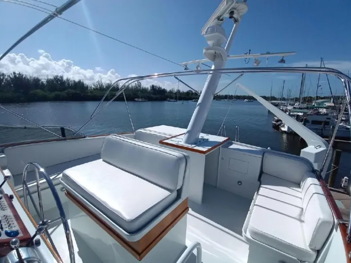  Yacht Photos Pics Flybridge of 1965 Burger 78' Cockpit Motor Yacht with white seating, docked by a marina.