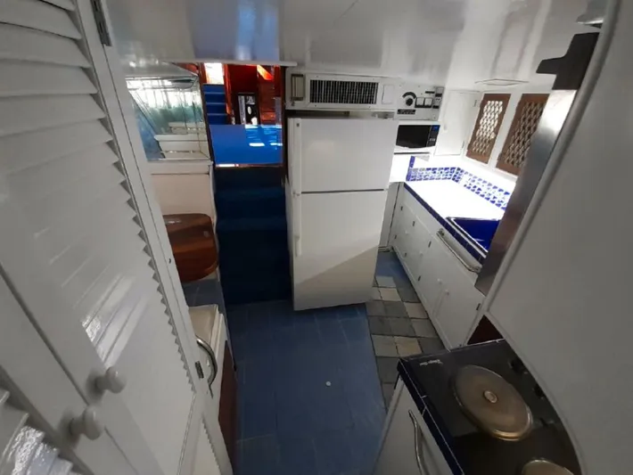  Yacht Photos Pics Interior of 1965 Burger 78' Cockpit Flybridge Motor Yacht kitchen with white cabinets and blue accents.