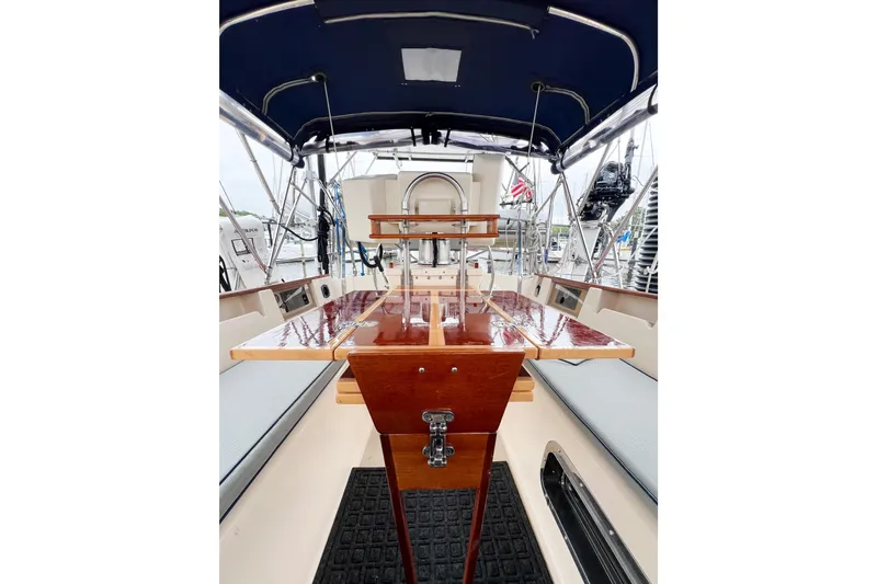 Delicia Yacht Photos Pics Cockpit of 1995 Island Packet 40 sailboat with polished wood table and blue canopy.