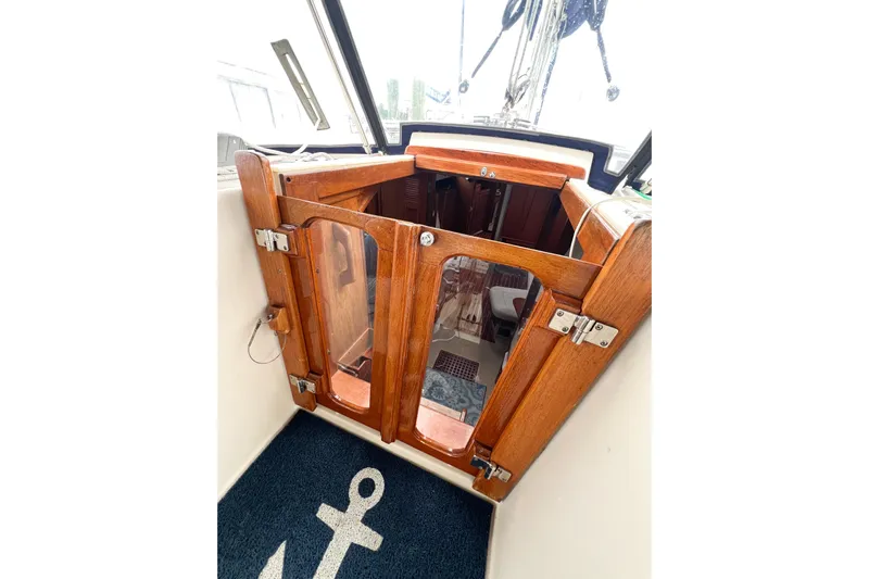Delicia Yacht Photos Pics Wooden cabin entrance of 1995 Island Packet 40 sailboat, featuring glass doors and nautical decor.