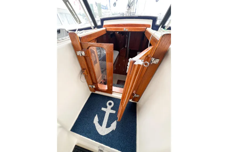 Delicia Yacht Photos Pics Interior view of 1995 Island Packet 40 sailboat with wooden doors and anchor-themed mat.