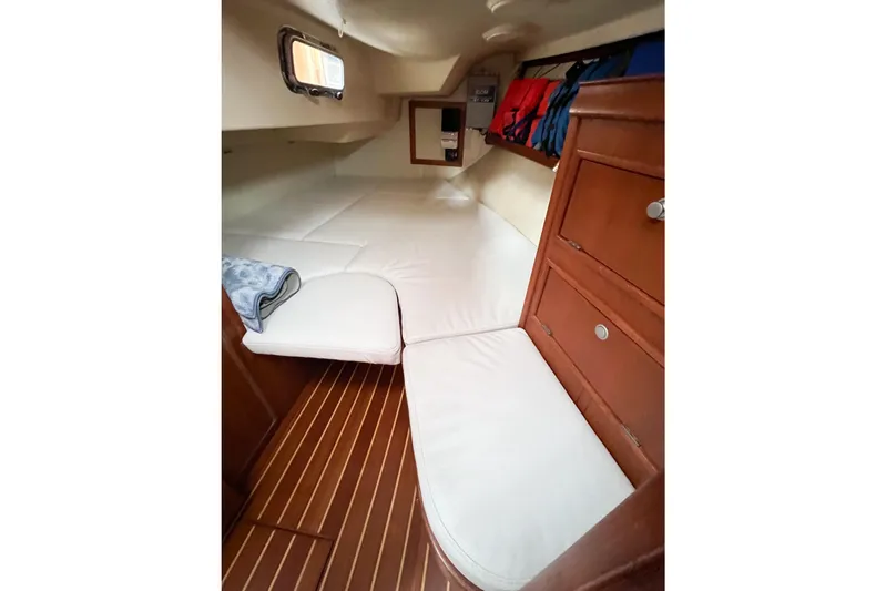 Delicia Yacht Photos Pics Interior cabin of 1995 Island Packet 40 sailboat with white cushions and wooden flooring.