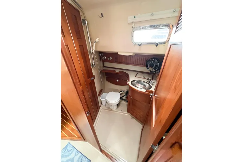 Delicia Yacht Photos Pics 1995 Island Packet 40 yacht bathroom with wooden cabinetry, sink, and toilet.