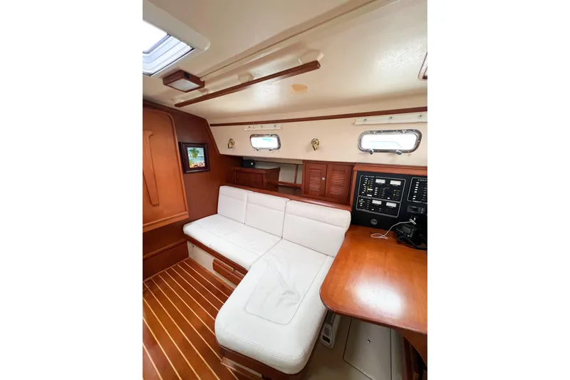 Delicia Yacht Photos Pics Interior of 1995 Island Packet 40 sailboat with white seating and wooden accents.
