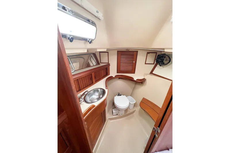 Delicia Yacht Photos Pics Interior of 1995 Island Packet 40 sailboat bathroom with sink, toilet, and wooden accents.