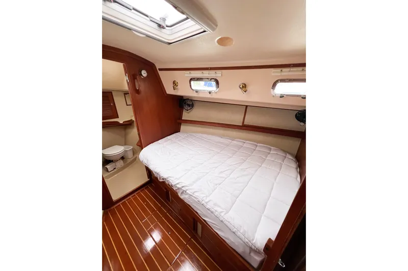 Delicia Yacht Photos Pics 1995 Island Packet 40 yacht cabin with bed, wooden flooring, and adjacent bathroom.