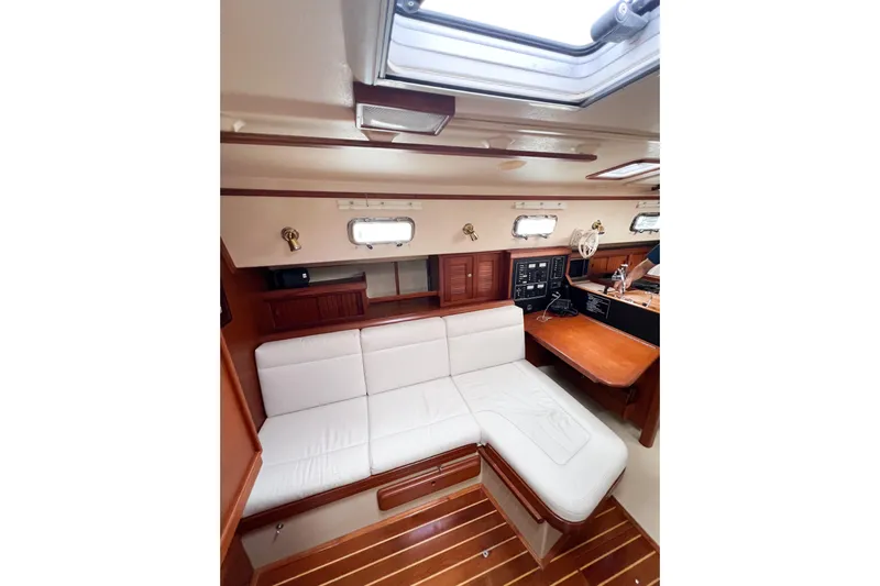 Delicia Yacht Photos Pics Interior of 1995 Island Packet 40 sailboat with white seating and wooden accents.
