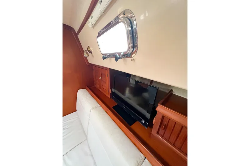 Delicia Yacht Photos Pics Interior of 1995 Island Packet 40 yacht with TV, wooden cabinetry, and porthole window.
