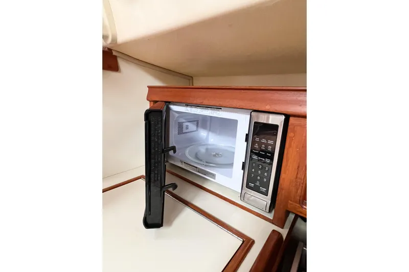 Delicia Yacht Photos Pics Microwave in 1995 Island Packet 40 yacht kitchen, open door, wooden cabinetry.