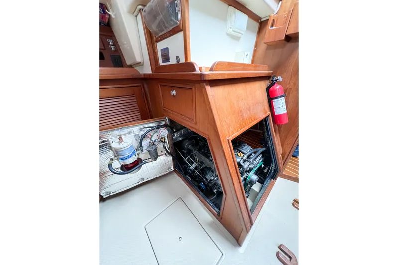 Delicia Yacht Photos Pics Engine compartment of a 1995 Island Packet 40 sailboat, featuring wooden cabinetry and a fire extinguisher.