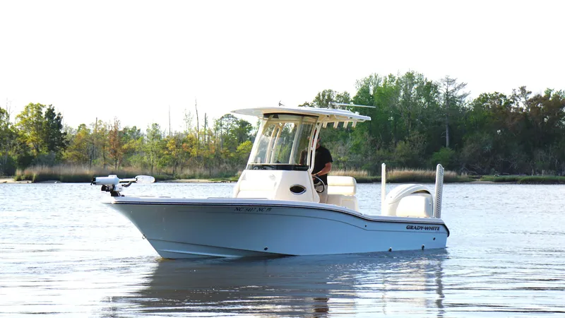  Yacht Photos Pics 2024 Grady-White 231 Coastal Explorer boat on calm water, surrounded by trees.