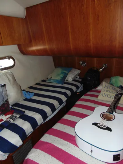 Dividend Yacht Photos Pics Cozy cabin interior of 2000 Tiara Yachts 5000 Express with striped bedding and guitar.