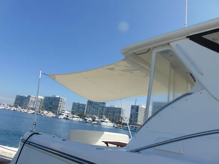 Dividend Yacht Photos Pics 2000 Tiara Yachts 5000 Express with sunshade, docked in marina, cityscape background.