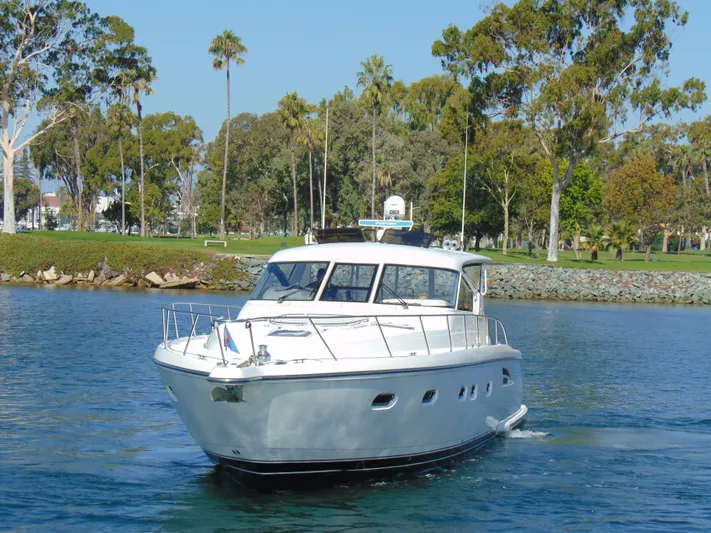 Dividend Yacht Photos Pics 2000 Tiara Yachts 5000 Express cruising on a serene lake with lush greenery.