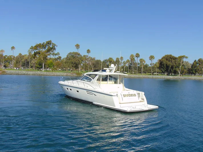 Dividend Yacht Photos Pics 2000 Tiara Yachts 5000 Express cruising on a serene lake with palm trees.