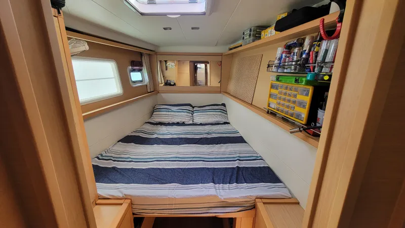 Momentum Yacht Photos Pics Cozy cabin interior of 2012 Lagoon 450 F catamaran with striped bedding and storage shelves.