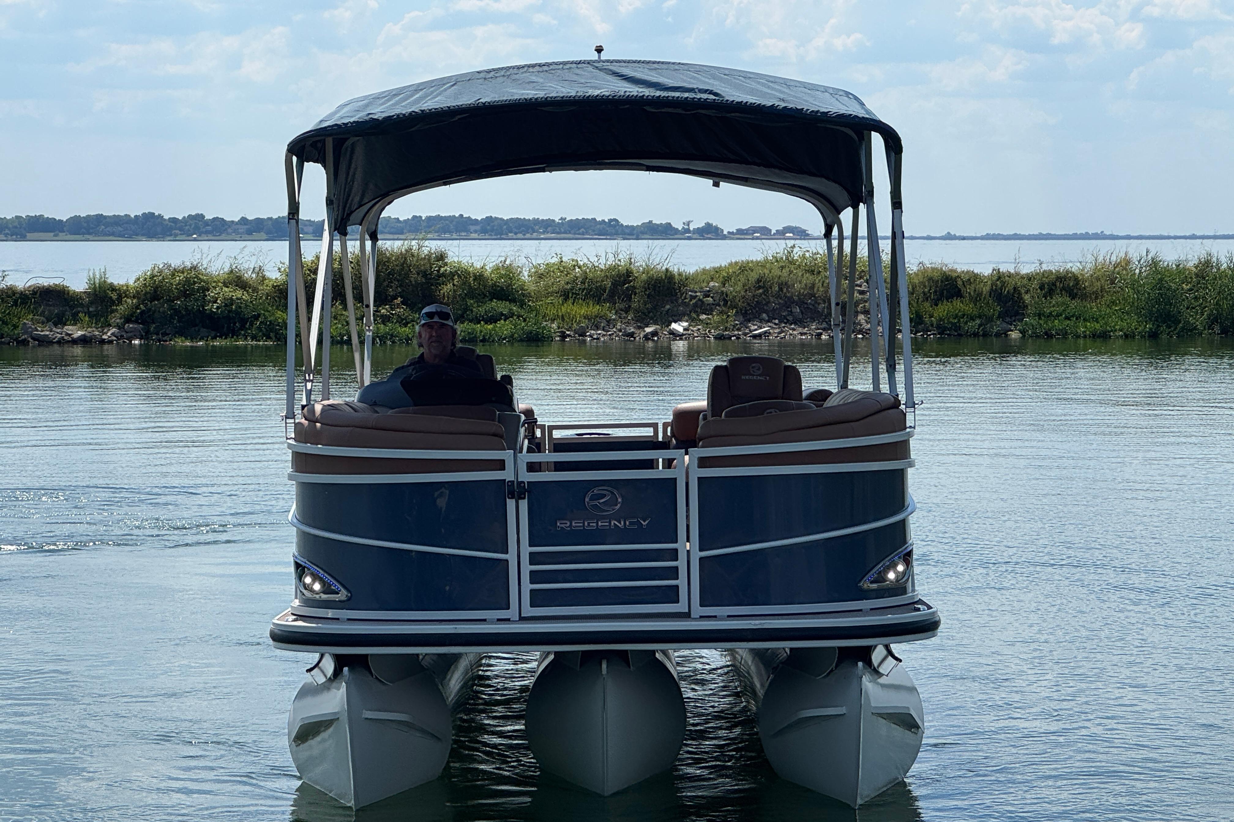 2017 Regency 254 LE3 pontoon boat on a calm lake with canopy.