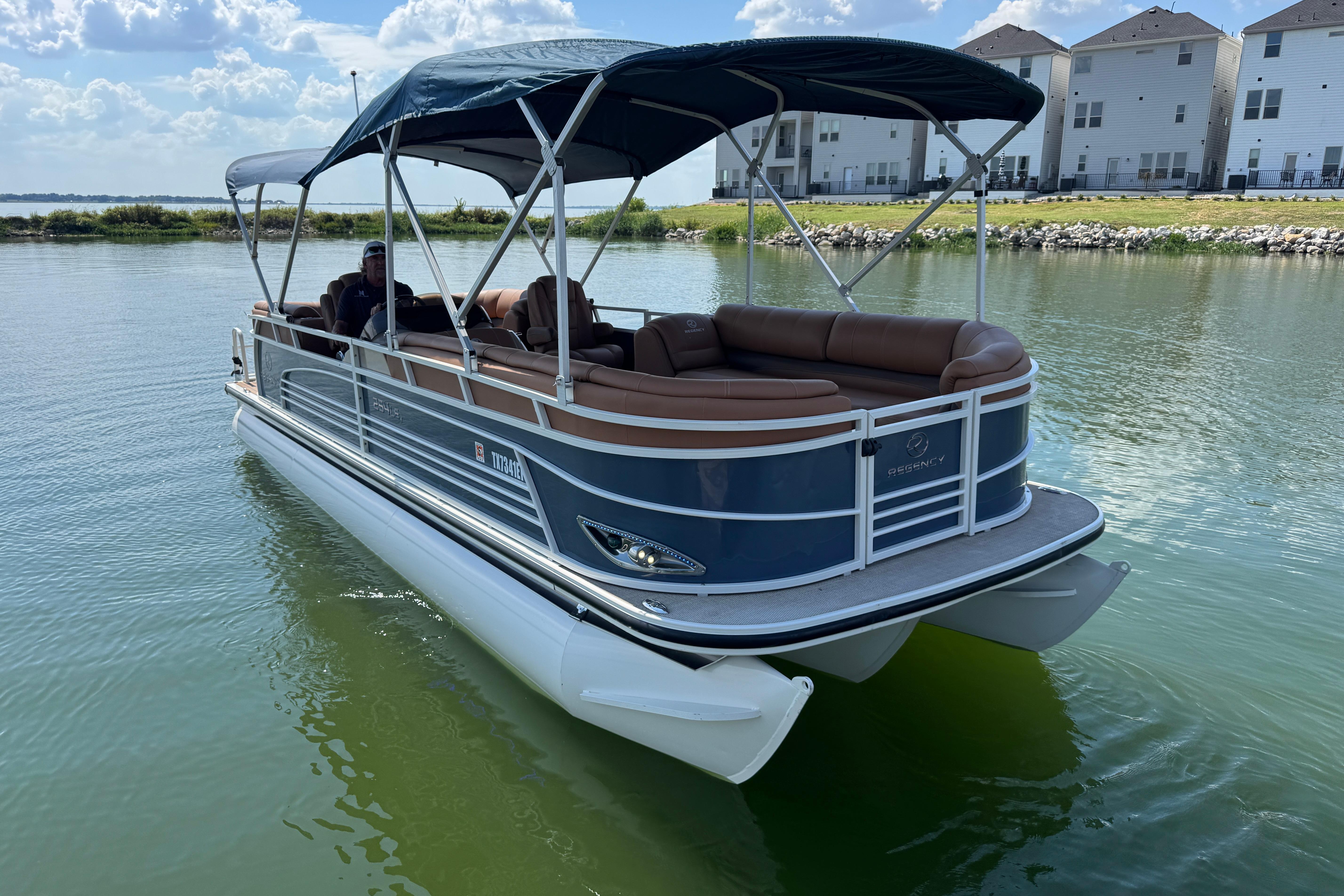2017 Regency 254 LE3 pontoon boat on calm water, featuring a canopy and comfortable seating.