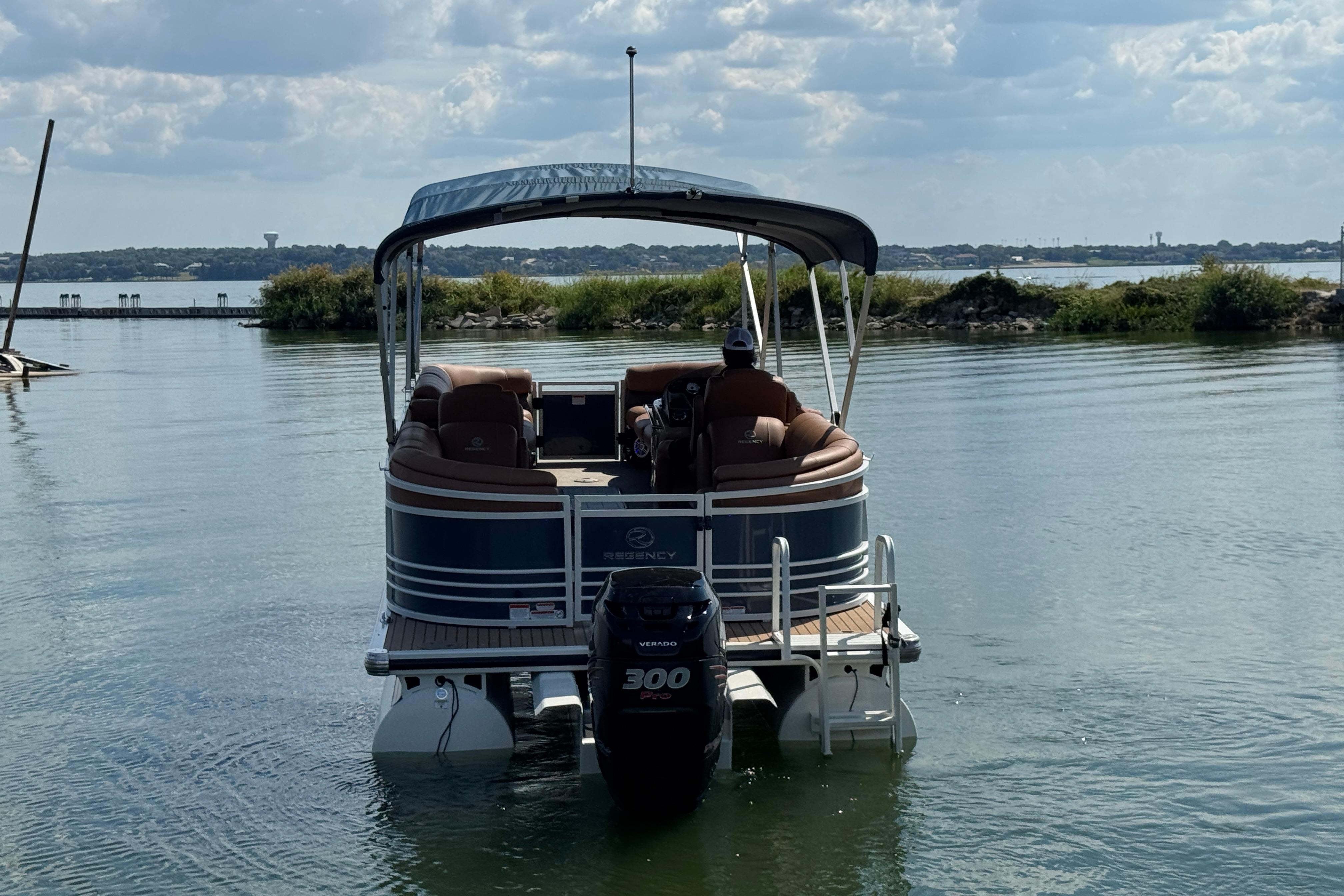 2017 Regency 254 LE3 pontoon boat on a calm lake under a cloudy sky.