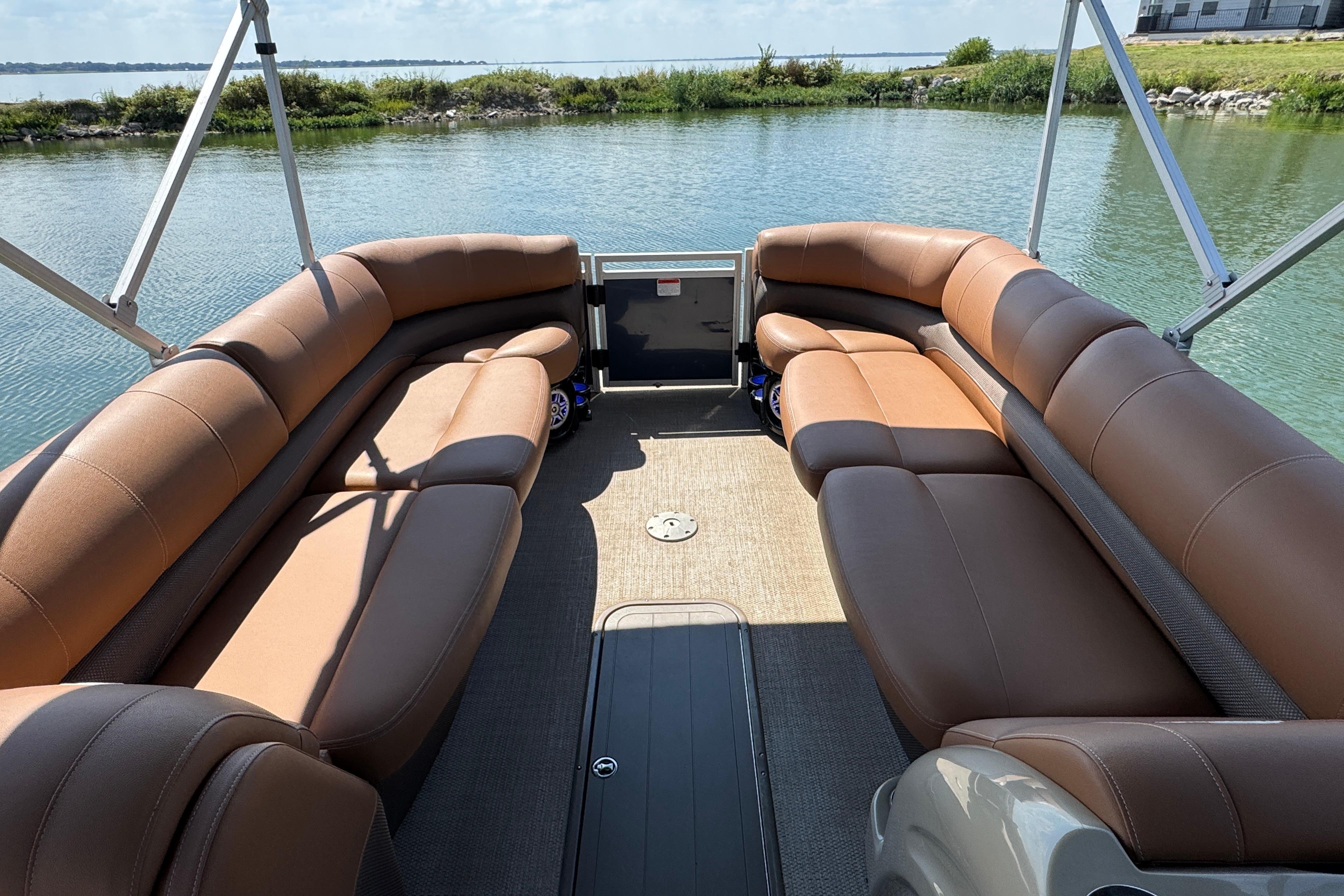 Luxurious seating on 2017 Regency 254 LE3 pontoon boat, docked by serene water.
