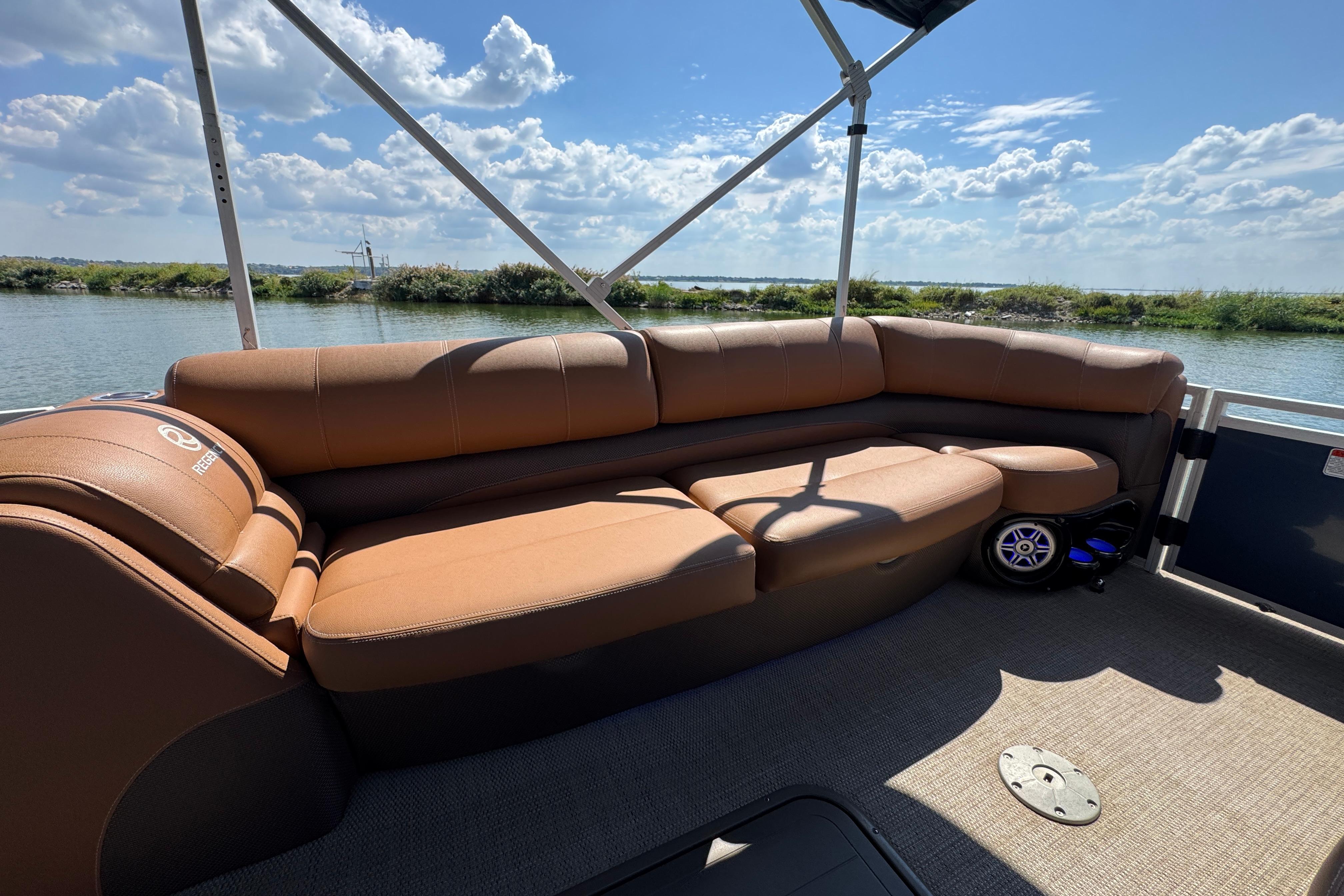 2017 Regency 254 LE3 pontoon boat with brown seating, on a sunny day by the water.