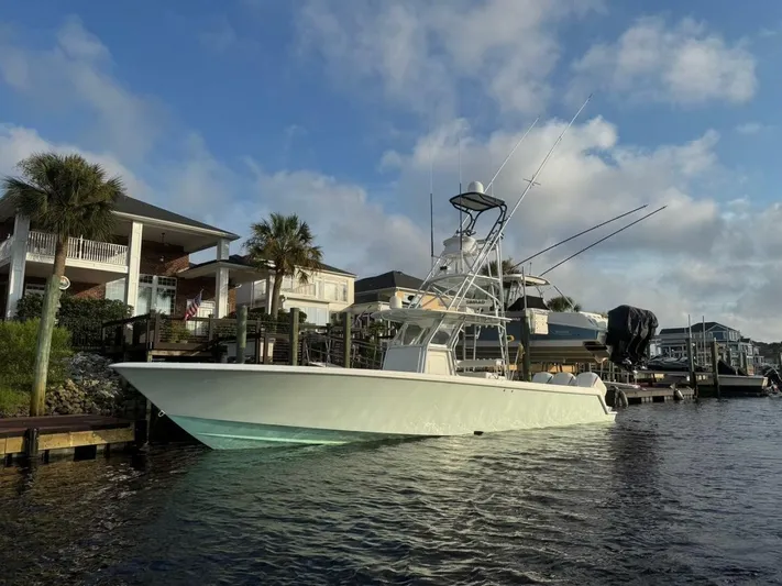Nauty C Bouys Yacht Photos Pics 2012 Contender 39ST boat docked by waterfront homes under a blue sky.