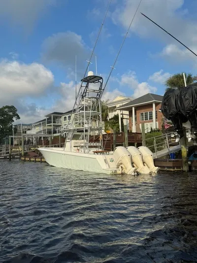 Nauty C Bouys Yacht Photos Pics 2012 Contender 39ST boat docked by waterfront homes under a blue sky.