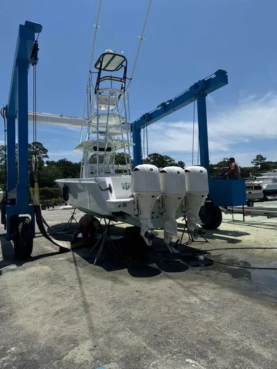 Nauty C Bouys Yacht Photos Pics 2012 Contender 39ST boat with triple outboard engines on a lift under clear sky.