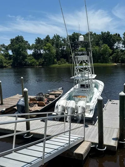 Nauty C Bouys Yacht Photos Pics 2012 Contender 39ST boat docked by a river, surrounded by lush greenery.