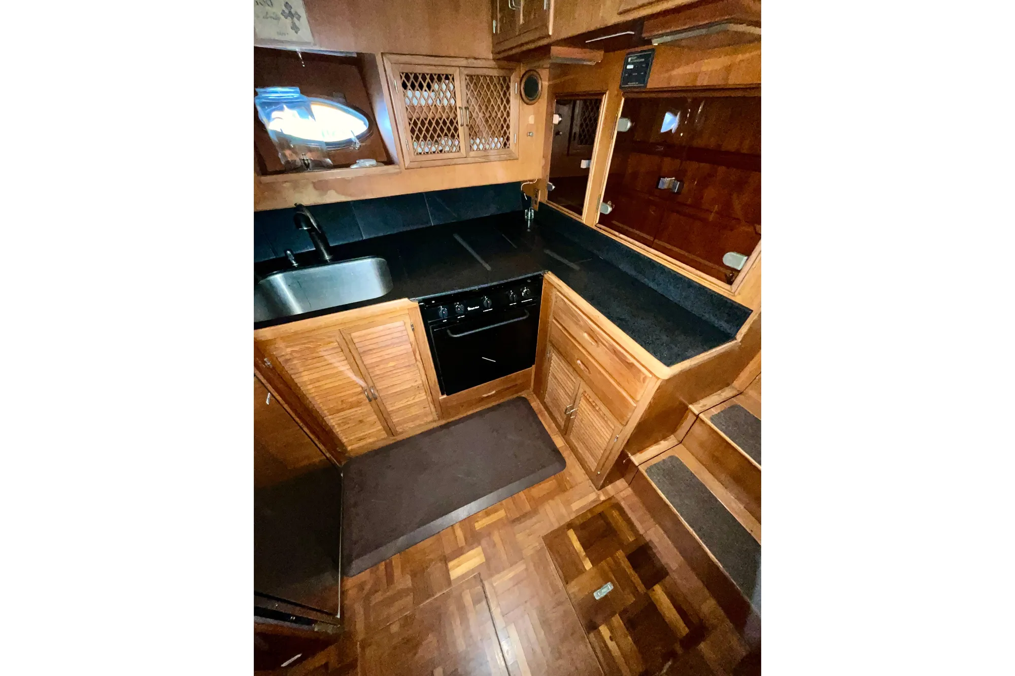 1987 Lien Hwa 47 Cockpit Motor Yacht kitchen with wood cabinetry and black countertops.