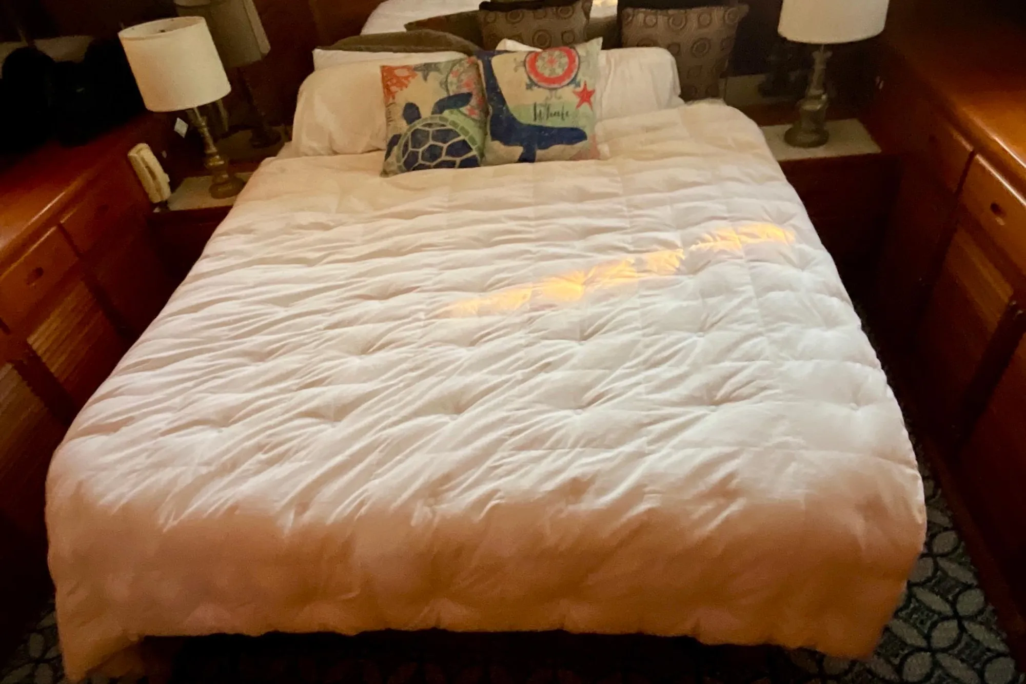 Cozy bedroom in 1987 Lien Hwa 47 Cockpit Motor Yacht with nautical-themed pillows.