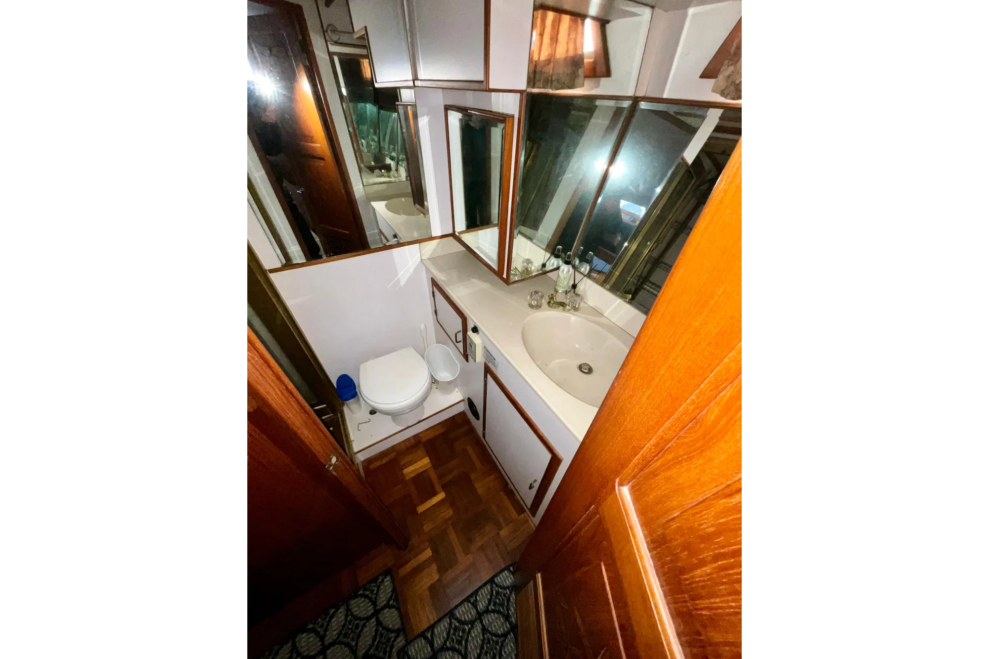 1987 Lien Hwa 47 Cockpit Motor Yacht bathroom with sink, toilet, and wooden cabinetry.