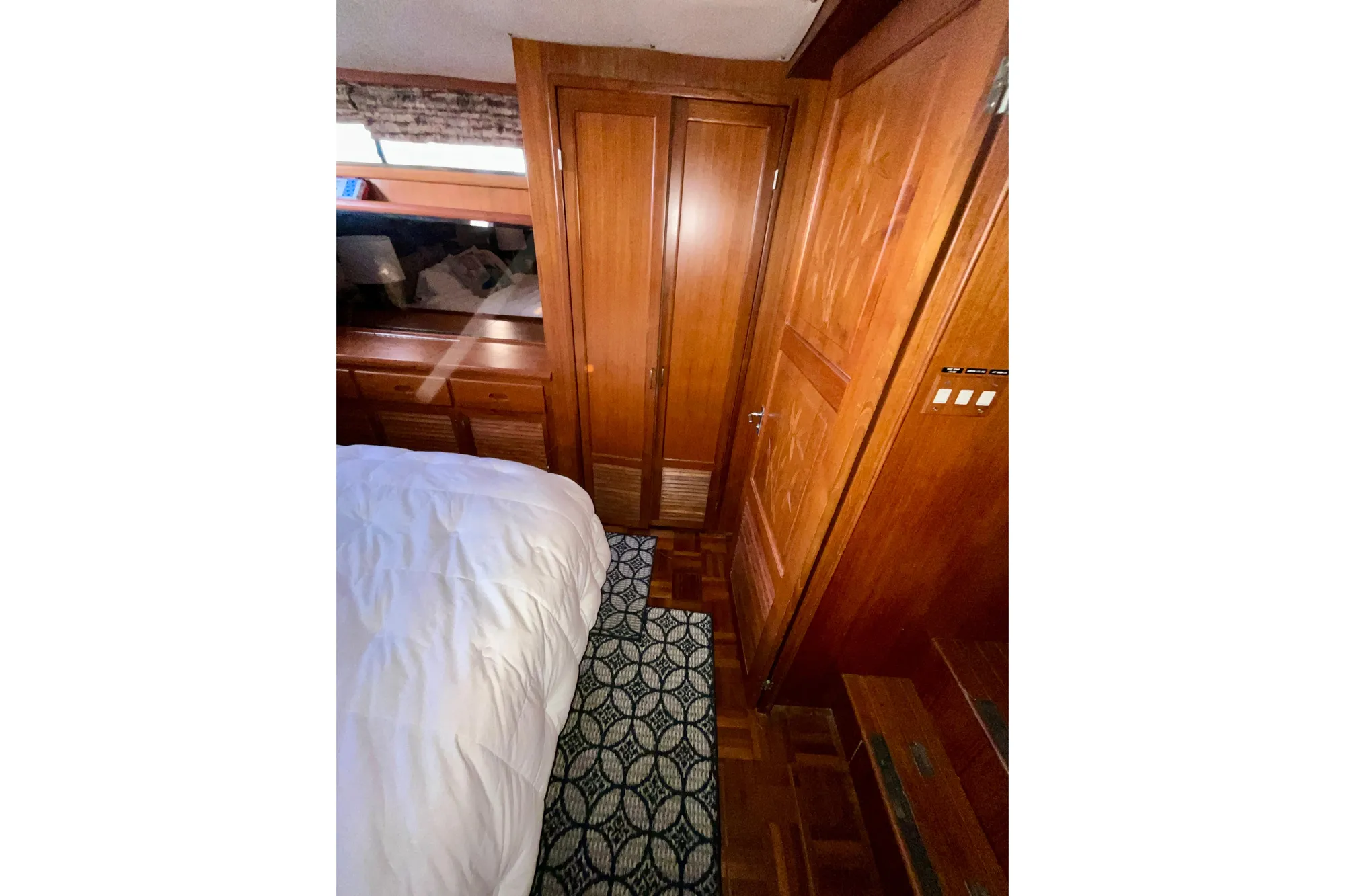 Interior of 1987 Lien Hwa 47 Cockpit Motor Yacht with wooden cabinetry and cozy bedding.