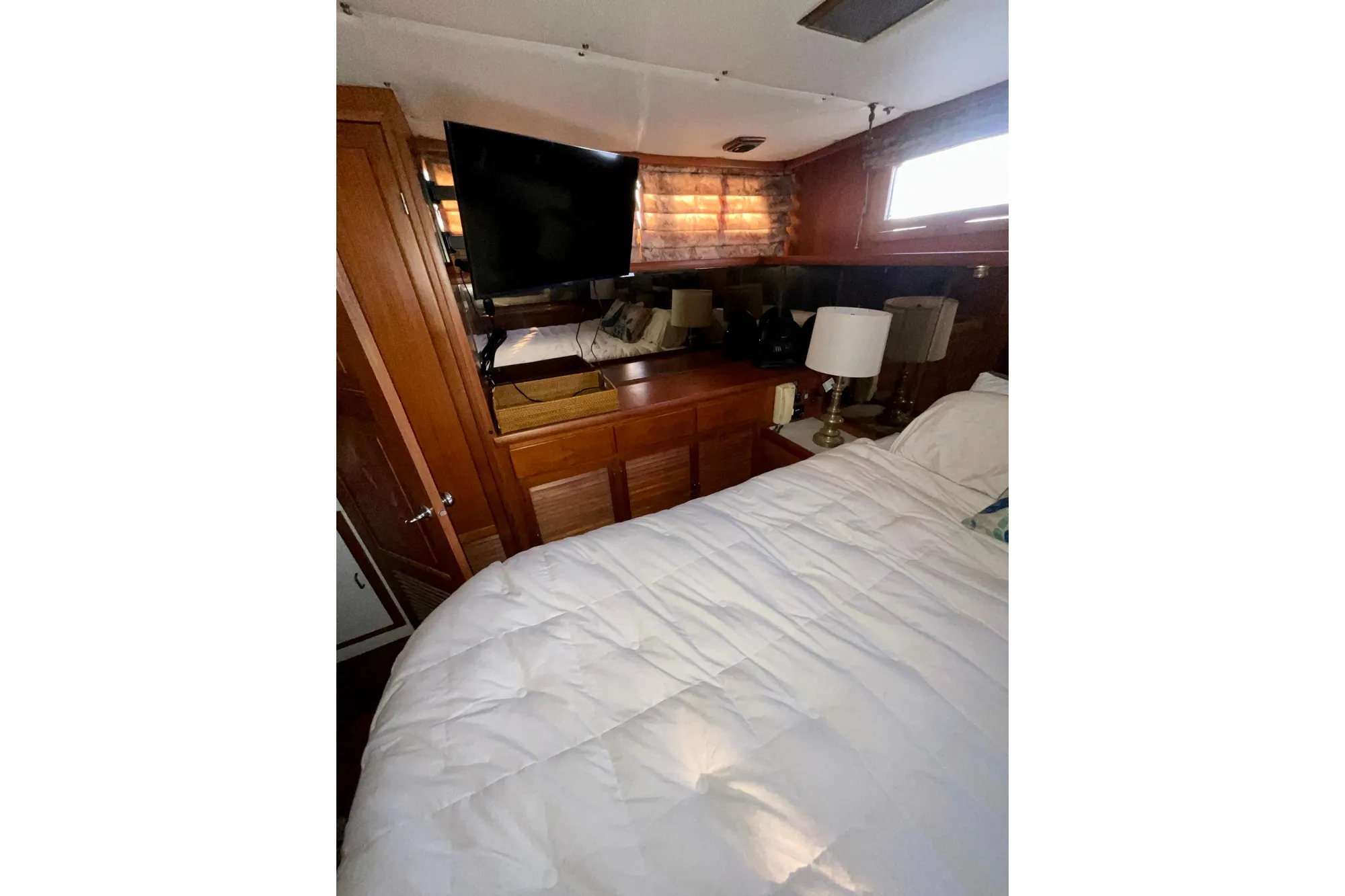 Interior of 1987 Lien Hwa 47 Cockpit Motor Yacht with bed, TV, and wooden cabinetry.