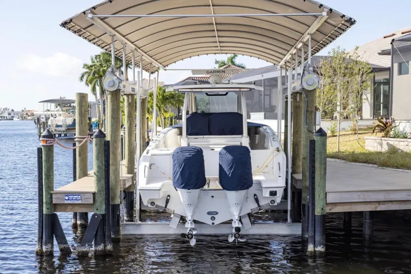  Yacht Photos Pics 2023 Pursuit S 328 Sport boat docked under canopy on waterfront.