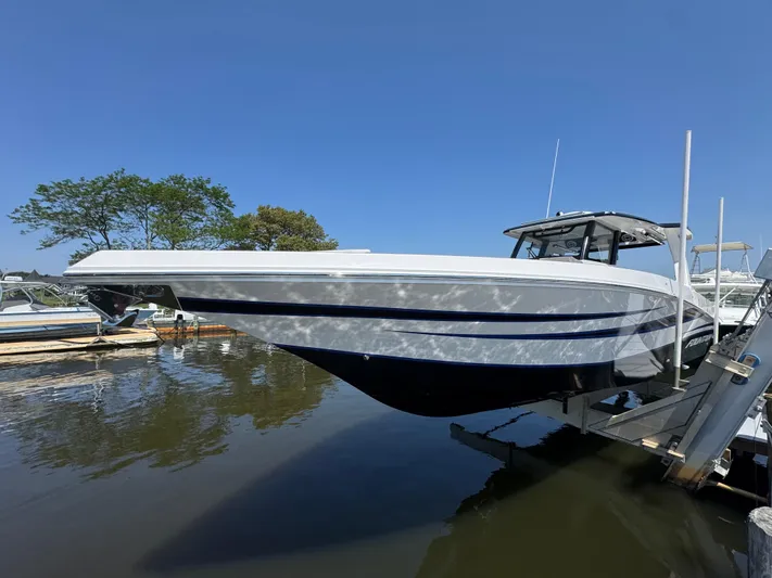  Yacht Photos Pics 2025 Fountain 38 SCX boat docked on a sunny day, reflecting on water.